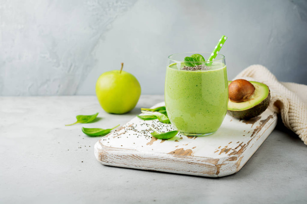 Vegetarian healthy green smoothie from avocado, spinach leaves, apple and chia seeds on gray concrete background. Selective focus. Space for text. - Фото, зображення