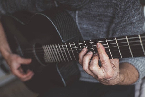 Elderly man playing carbon fiber guitar - Fotoğraf, Görsel