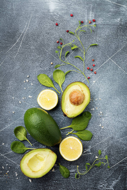 Food background with green vegetables: avocado, spinach, chavran leaves, red pepper and lemon on a dark old slate, stone or concrete background. Selective focus. Top view.Space for text. - Photo, image