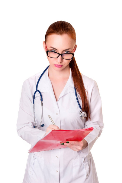 Красивая молодая женщина-врач в медицинском халате с медицинскими записями. Медсестра делает записи в медицинской карте
 - Фото, изображение