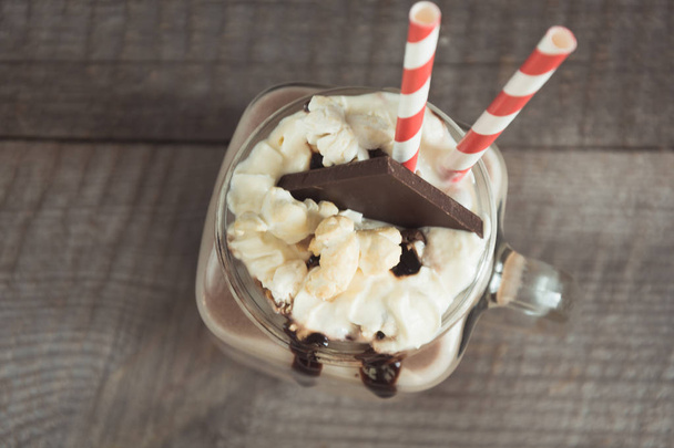 Chocolate coffee milkshake with whipped cream served in glass mason jar on gray wooden background. Sweet drink. View from above. - Foto, Imagem
