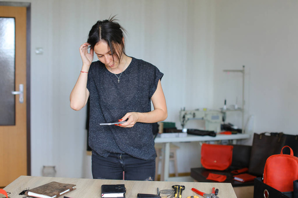 Девушка фотографирует ноутбук ручной работы с помощью смартфона
. - Фото, изображение
