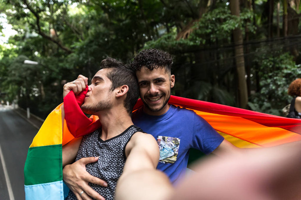 Gay Couple Taking a Selfie with Rainbow Flag in the Park - Photo, Image