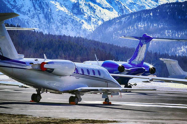 Private jets, planes and helicopters in the beautiful snow covered mountains of alps in St Moritz Switzerland - Photo, Image