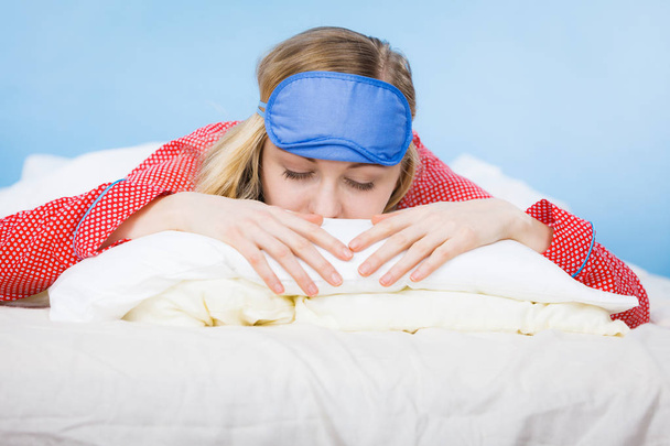 Young woman wearing sleeping eye band in bed - Fotó, kép