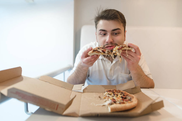 głodny człowiek człowieka z brodą, jedzenie pizzy z kartonu. Człowiek z brodą posiada kawałki pizzy w jego ręce i ma zamiar je jeść. - Zdjęcie, obraz