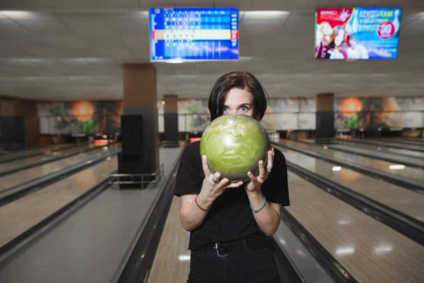 Portrét krásné mladé dívky s bowlingovou kouli v rukou pozadí skladeb. Umístěte na hře v kuželky. - Fotografie, Obrázek