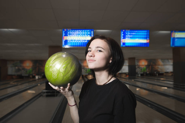 Portrét pozitivní dívka hrát kuželky. Dívka s bowlingovou kouli v ruce. - Fotografie, Obrázek