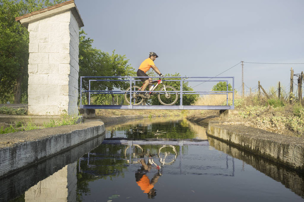 MTB biker crossing a bridge over irrigation canal, Extremadura,  - Photo, Image