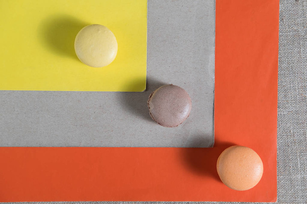 three colored cake macarons are on colored paper abstraction - Photo, image