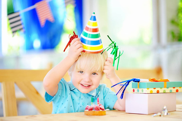 Cute little boy having fun and celebrate birthday party with colorful decoration and cake - Foto, imagen