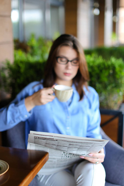 Charmante vrouw lezen van de krant in restaurant en het drinken van thee - Foto, afbeelding