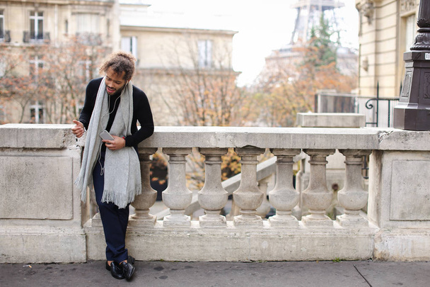 Mulatte genießt Smartphone und Kopfhörer mit Eiffelturm - Foto, Bild