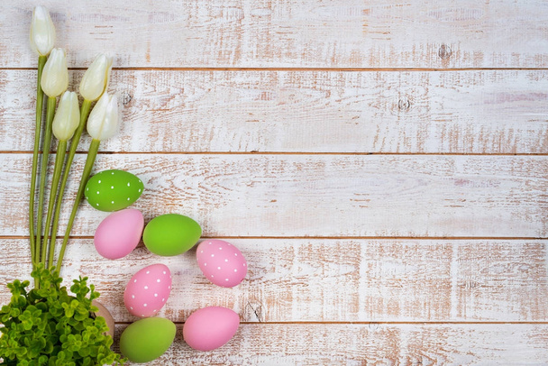Värikäs pääsiäismunia ja tulppaanit yli valkoinen puinen pöytä
 - Valokuva, kuva