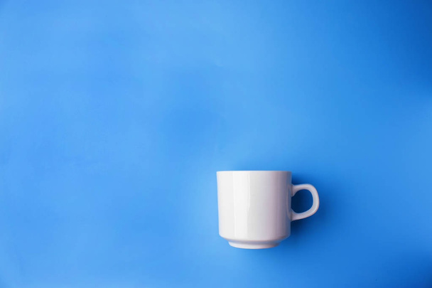 white cup on blue background with copy space - Foto, Imagem