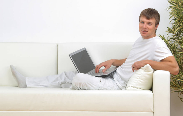 Very focused young man using laptop while sitting comfortably. - Valokuva, kuva