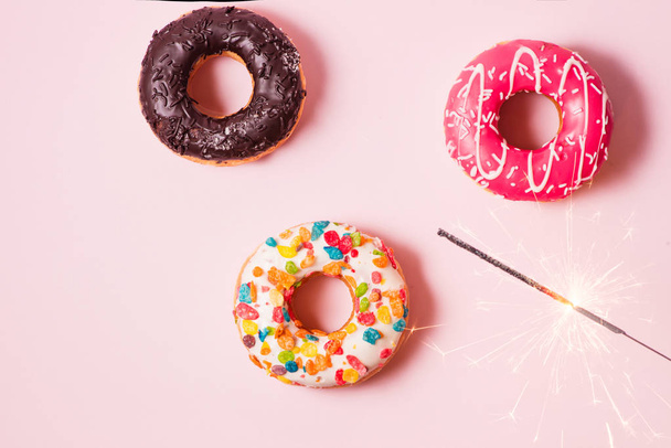 köstliche Donuts zum Geburtstag auf pastellrosa Hintergrund. - Foto, Bild