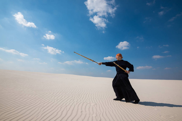 Caucasian man is practicing kendo in a desert - Foto, imagen