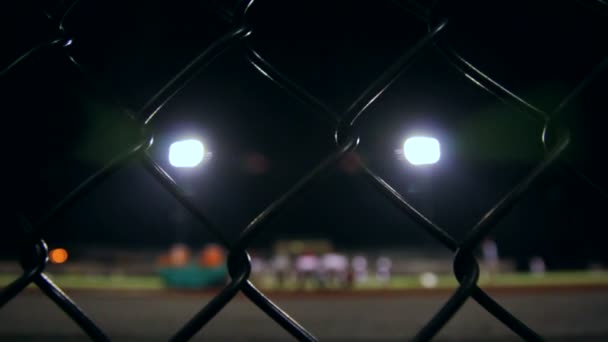 κουκλίτσα πίσω από ένα φράχτη βλέποντας μια υψηλή σχολική ομάδα ποδοσφαίρου - Πλάνα, βίντεο