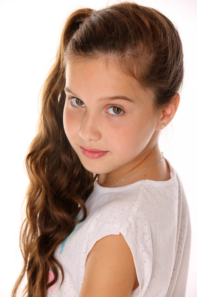 Portrait of a pretty young teenage girl close-up. Adorable preteen with dark hair and charming face on a white background. The image of children's summer fashion. - Foto, Imagen