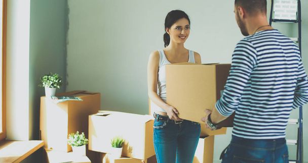 Happy young couple unpacking or packing boxes and moving into a new home - Foto, imagen