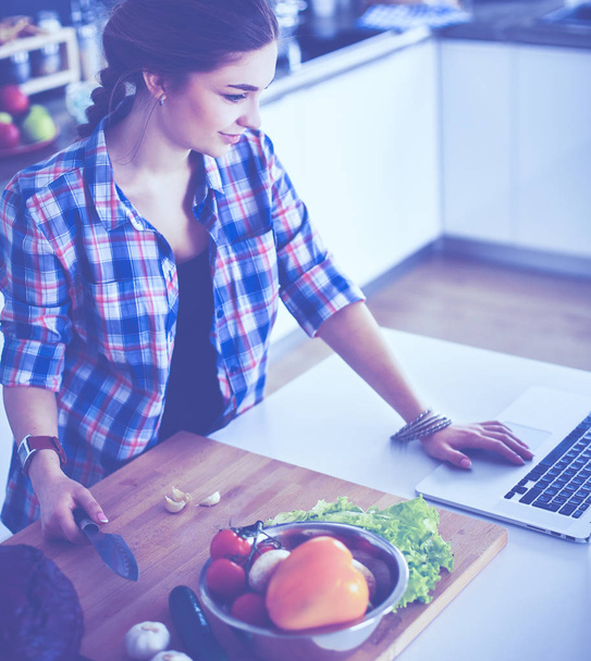 Young woman cutting vegetables in kitchen near desk - Foto, Imagem