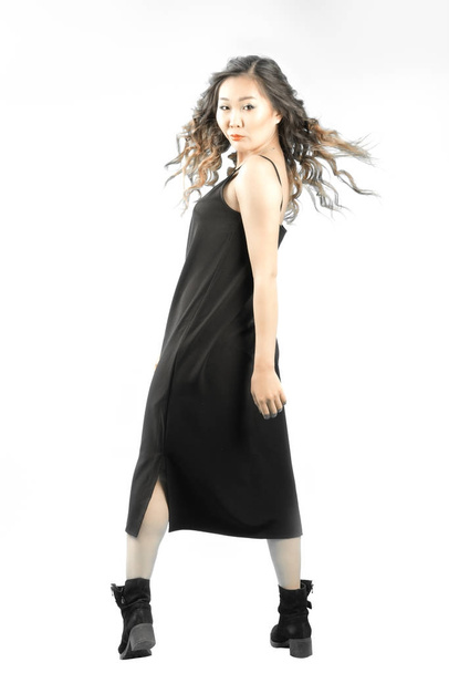 повний довгий портрет азіатської жінки в чорному платті і чоботях, що стоять спиною і повертають обличчя для Гарварду з розвитком волосся
 - Фото, зображення