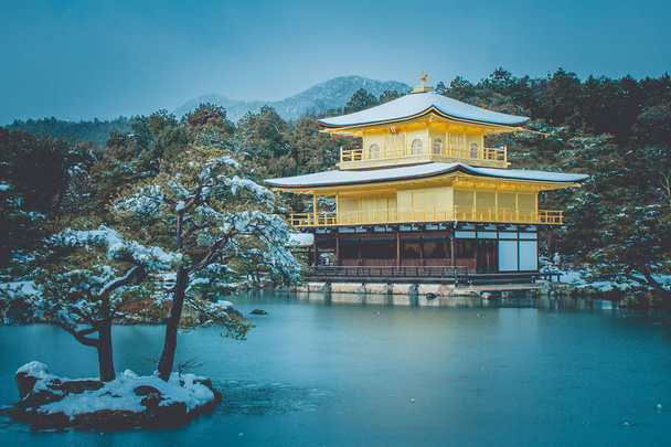 Hermosa temporada de invierno del Pabellón de Oro del Templo Kinkakuji con nieve blanca cayendo en Kyoto, Japón en estilo vintage
. - Foto, imagen
