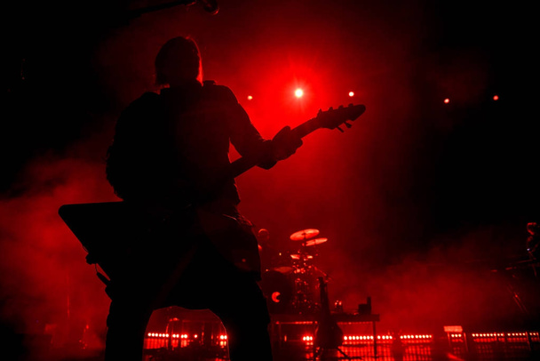 Silhouette of guitar player on stage. Dark background, smoke, red spotlights - Foto, imagen