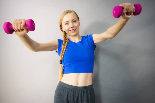 Teenage woman working out at home with dumbbell - Fotografie, Obrázek
