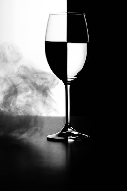 a glass of water and smoke on a black and white background  - Fotó, kép