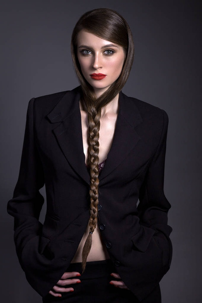 Beautiful woman in a black jacket with a creative hairdress on a - Фото, изображение