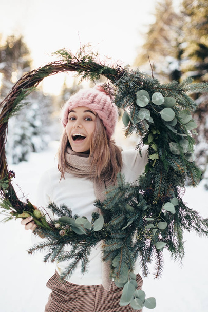 Blonde young lady with christmas wreath in winter forest - Photo, image