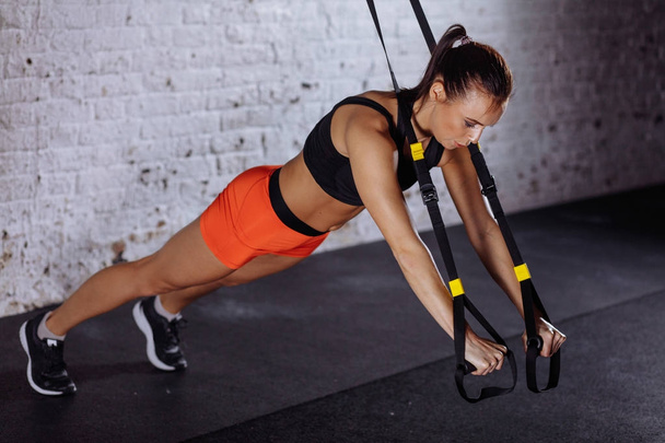 Women doing push ups training arms with trx straps in gym - Foto, Imagen