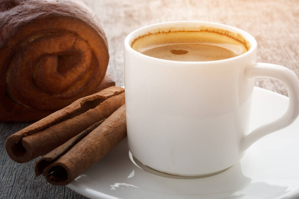 木製の背景の白いプレートに香り豊かなコーヒーのカップ - 写真・画像