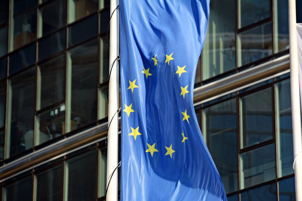 Europese Unie vlaggen, vliegen en zwaaien met glazen wand kantoorgebouw achtergrond - Foto, afbeelding