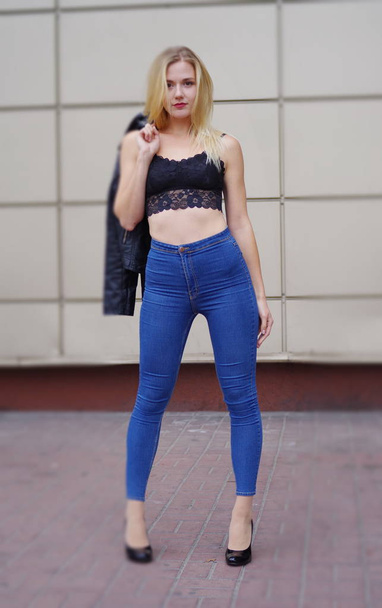 Güzel kız mavi kot pantolon ve siyah kırpma üst poz - Fotoğraf, Görsel