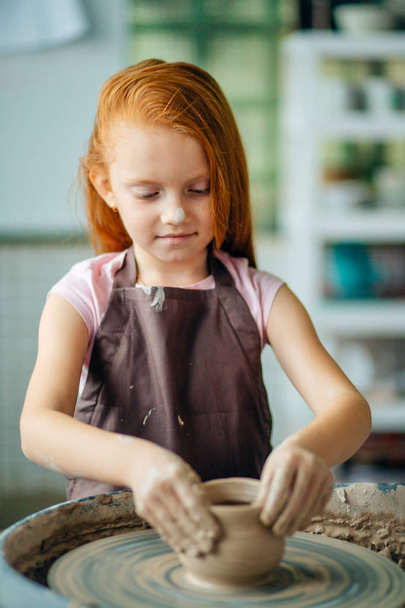 redhead Child sculpts from clay pot. workshop on modeling on potters wheel. - 写真・画像