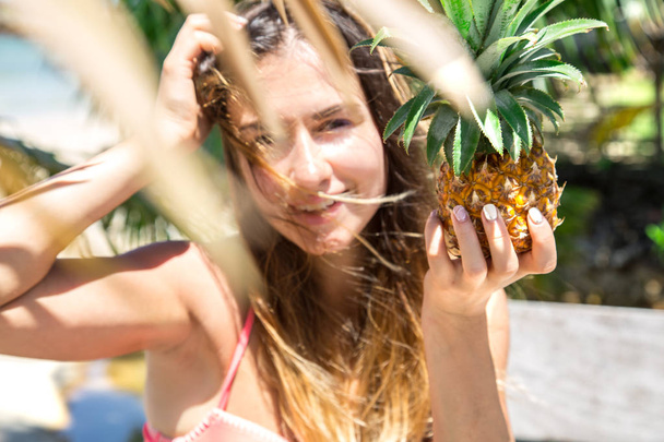 beautiful girl in a straw hat, with a fresh pineapple in hand on - Foto, afbeelding