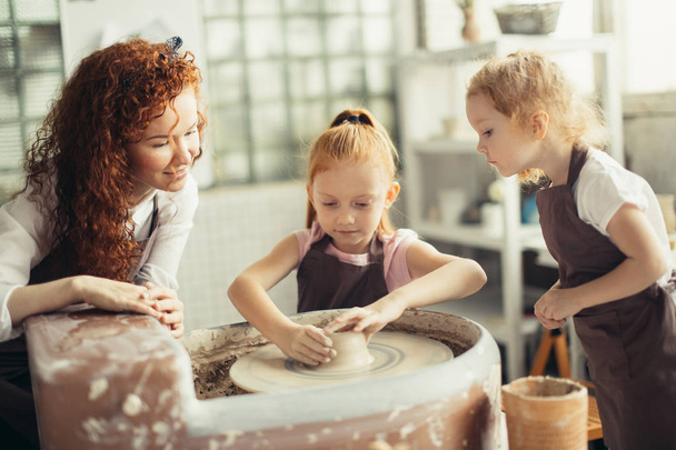 mother and two redhead daughters made clay cup with pottery wheel - Fotografie, Obrázek