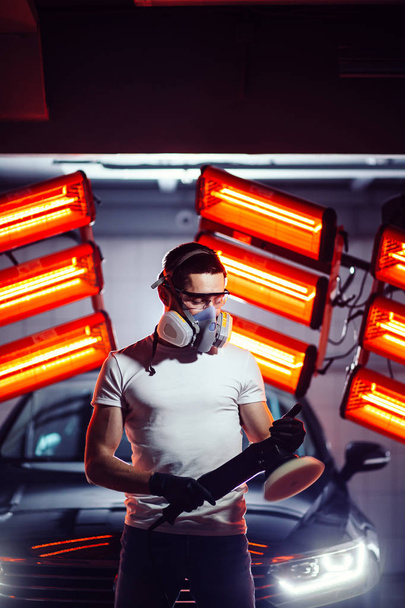 man wearing protective mask and glasses holding polishing machine - Foto, afbeelding