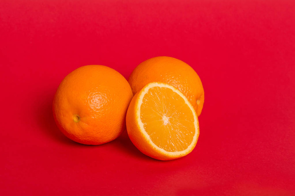 Ripe oranges on a red background. Juicy half orange. - Φωτογραφία, εικόνα