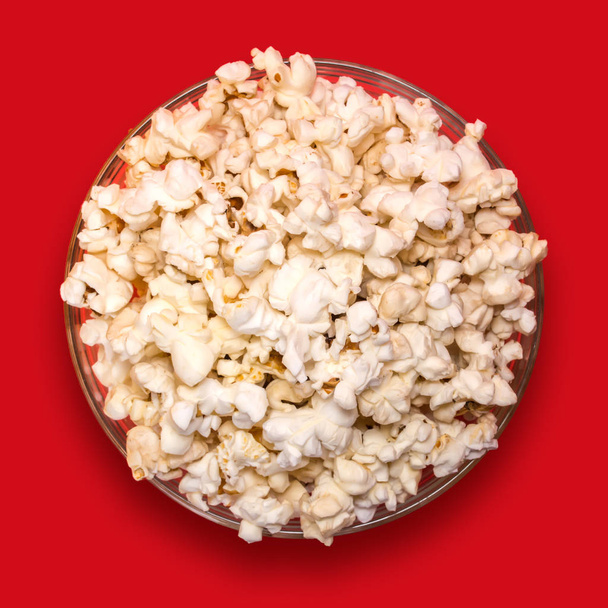 Popcorn in a transparent plate on a red background. - Fotografie, Obrázek