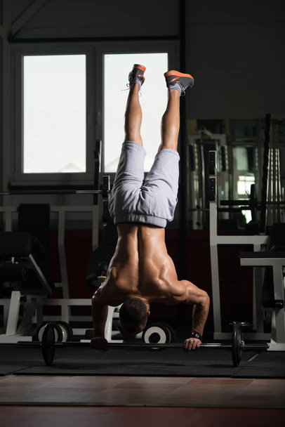 Bodybuilder Exercising Push-Ups On Barbell In Elevation Mask - 写真・画像