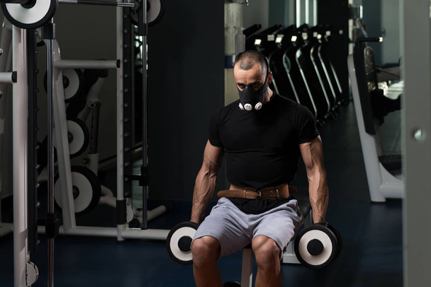 Man With Dumbbells Exercising Biceps In Elevation Mask - Foto, Imagen