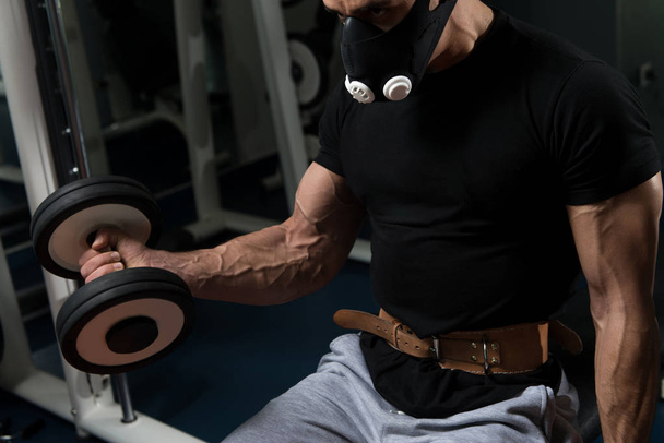 Man With Dumbbells Exercising Biceps In Elevation Mask - 写真・画像