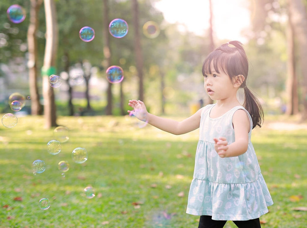 Linda niña jugando burbuja en el jardín
. - Foto, imagen