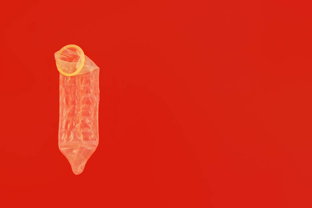 Condón masculino sobre fondo rojo con espacio de copia para anticoncepción y concepto de sexo de seguridad
 - Foto, Imagen