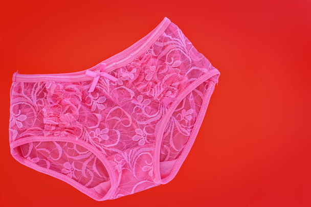Рожеві жіночі мереживні труси на червоному тлі для концепції одягу
 - Фото, зображення