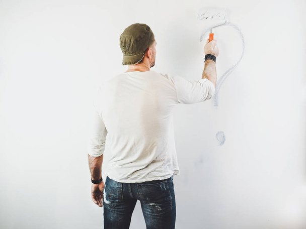 guy erasing a question mark on a white wall - Φωτογραφία, εικόνα